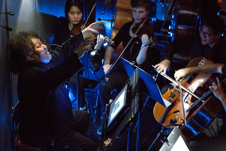 A conductor and musicians in an orchestra pit