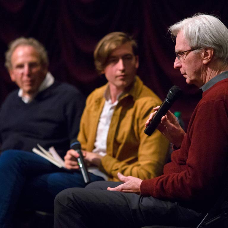 Three people talk on stage.