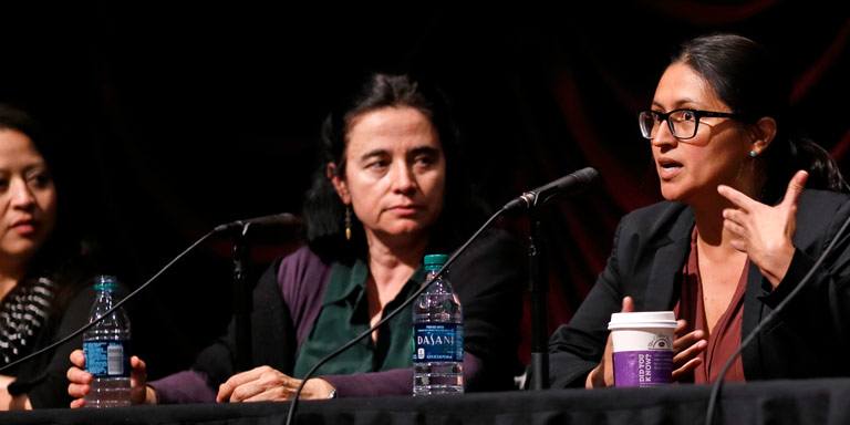 Three panelists speak before an audience.